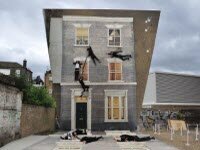 Художник создает иллюзию дома, которая на самом деле всего лишь отраженная модель на земле