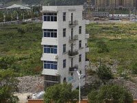 Китайская женщина остается жить в щипком многоквартирном доме