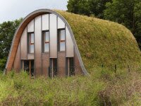 Дом в форме холма с растущими на нем растениями обеспечивает теплоизоляцию