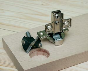 Работая с упором или направляющей и используя специальную фрезу, делают пазы для установки мебельных петель